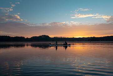 Eine Frau und ein Mann machen eine Kanutour bei Sonnenuntergang auf dem See