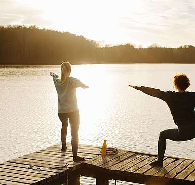 Zwei Frauen machen Yoga am See