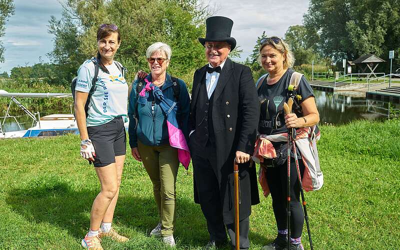 Drei Frauen in sportlicher Kleidung posieren mit einem als Theodor Fontane verkleideten Mann für die Kamera.