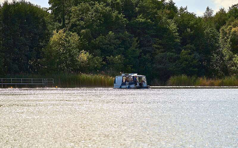 Ein kleines, voll besetztes Boot fährt auf einem hell glitzernden See