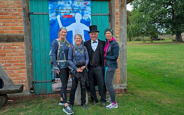 Drei sportlich gekleidete Frauen lassen sich vor einer Fotowand mit Theodor Fontane fotografieren.