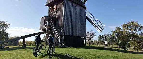 Zwei Radfahrer blicken auf die Bockwindmühle Vehlefanz