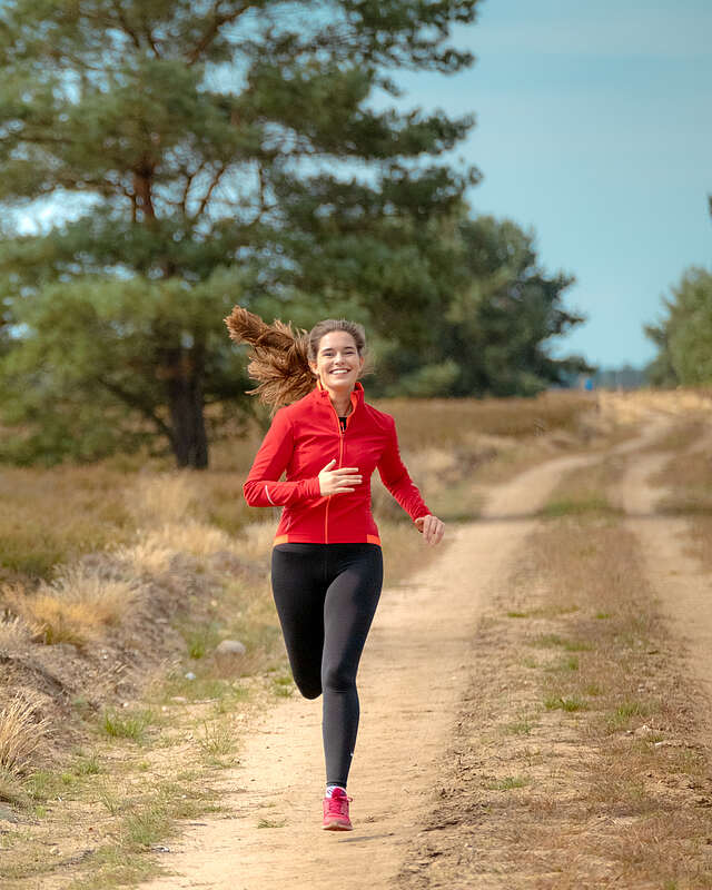 Eine junge Frau joggt auf einem Sandweg durch die Kyritz-Ruppiner Heide