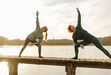 Zwei Frauen machen Yoga am See